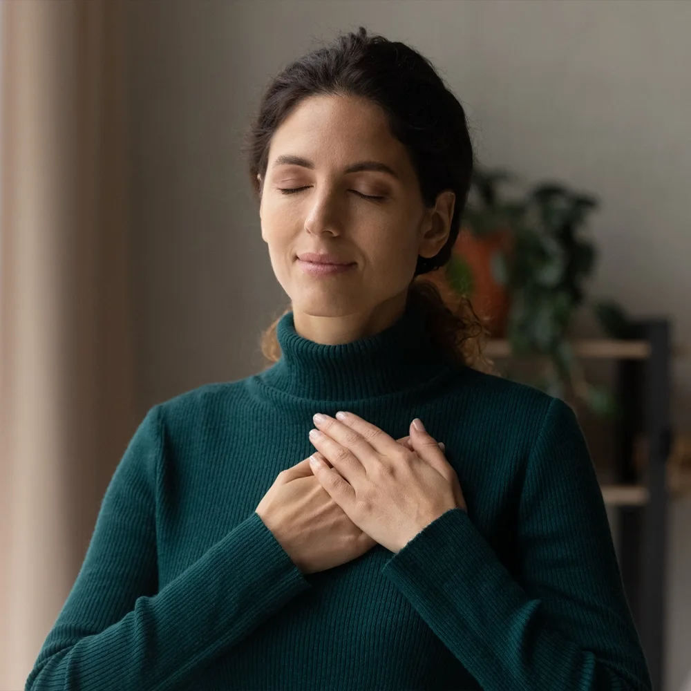 Woman taking a calm, focused moment with her hand on her chest